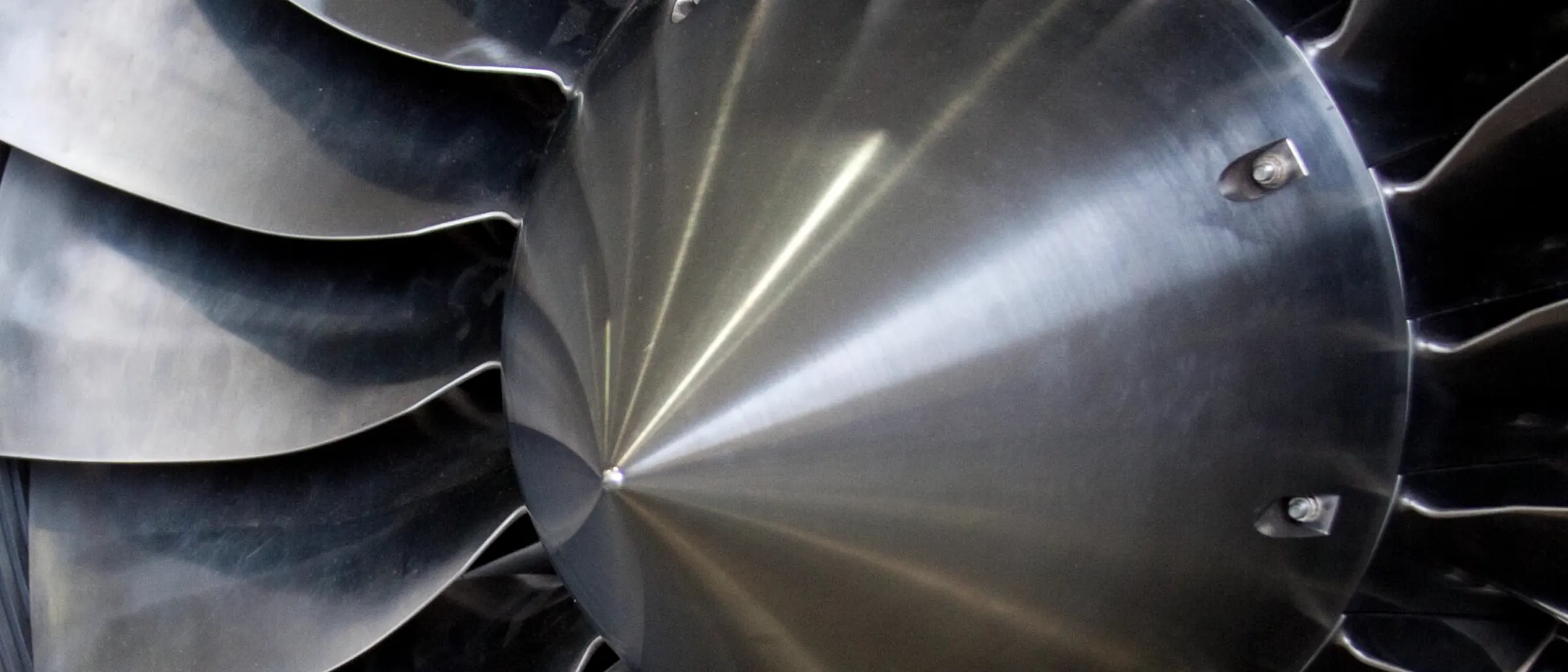 Close view into the intake of a turbofan engine, fan blades filling the frame.