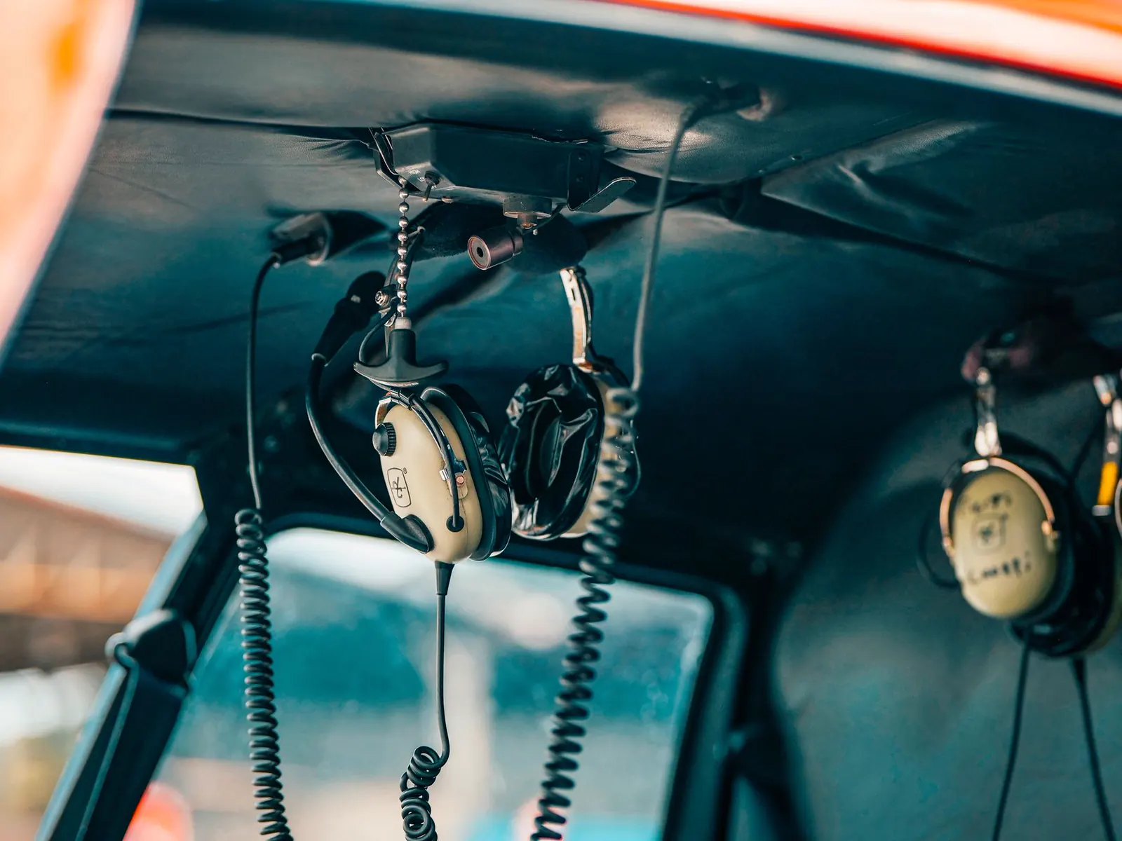 Aviation headsets hanging in an aircraft cockpit.