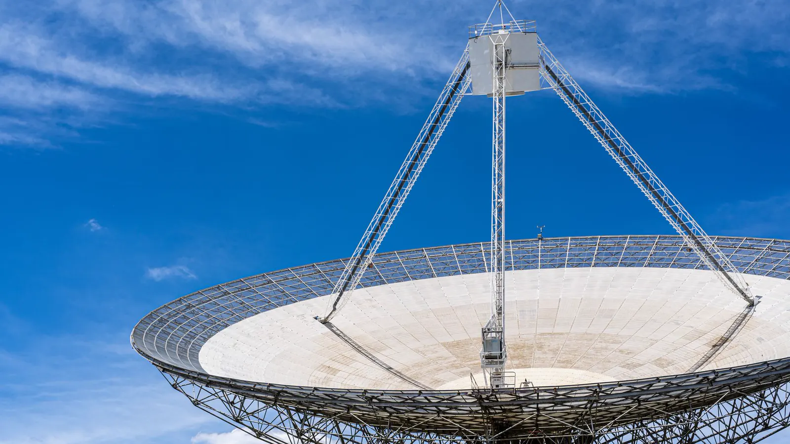 A large steerable radio telescope, its dish held in an open lattice frame against a clear sky.