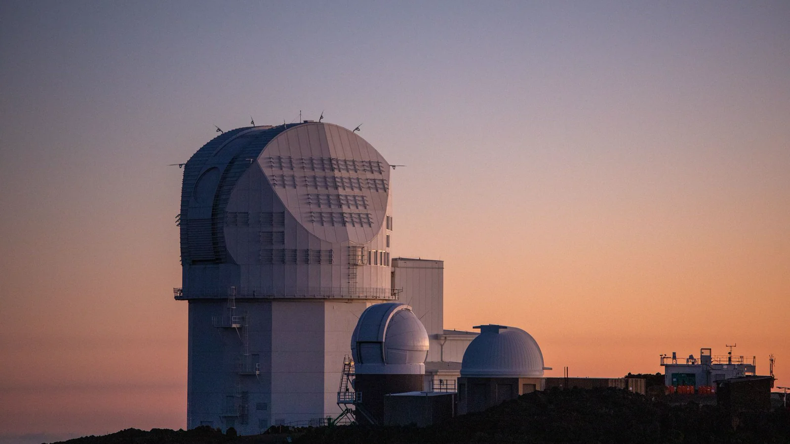 A solar observatory building under a coloured sunset sky.