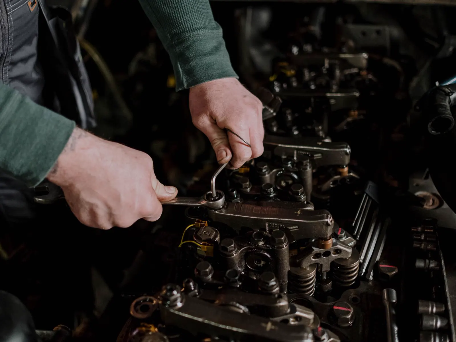A mechanic using hand tools on an engine, hands and the work in frame.